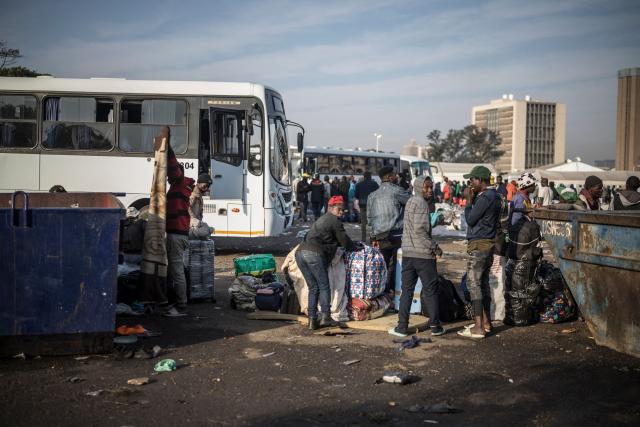 Undocumented migrants line up near buses at the Durban Drive In in Durban, on June 29, 2026 preparing to leave before the shutting down of the camp and the operation will be transferred to the border with Zimbabwe. South Africans President Cyril Ramaphosa vowed on June 25 to crush any attempts to destabilise the nation during planned anti-immigrant marches next week, amid a wave of xenophobia. Citizen-led groups have set Tuesday 30 as a deadline for undocumented foreigners to leave and called for nationwide marches against illegal immigration, marking a crescendo in months of protests that have at times turned violent. (Photo by MARCO LONGARI / AFP)