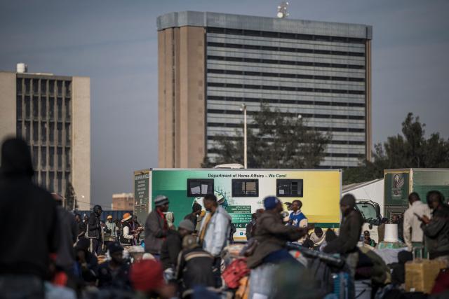 Undocumented migrants line up near a bus at the Durban Drive In in Durban, on June 29, 2026 preparing to leave before the shutting down of the camp and the operation will be transferred to the border with Zimbabwe. South Africans President Cyril Ramaphosa vowed on June 25 to crush any attempts to destabilise the nation during planned anti-immigrant marches next week, amid a wave of xenophobia. Citizen-led groups have set Tuesday 30 as a deadline for undocumented foreigners to leave and called for nationwide marches against illegal immigration, marking a crescendo in months of protests that have at times turned violent. (Photo by MARCO LONGARI / AFP)
