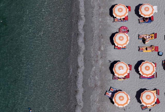 This aerial photograph shows people sunbathing on a beach in Durres, western Albania, on June 29, 2026. Europe's deadly heatwave pushed east with hundreds of millions still sweltering across the continent despite fleeting relief from overnight storms, notably in France and Belgium. (Photo by Adnan Beci / AFP)
