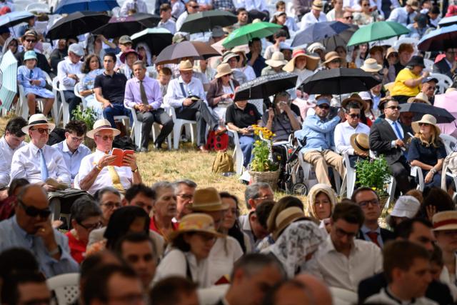 Worshippers protect themselves from the sun as they attend an ordination ceremony of the traditionalist Catholic Society of Saint Pius X (SSPX), in Econe, near Sion, western Switzerland, on June 29, 2026. Defying Vatican, Society of Saint Pius X will ordain its own bishops on July 1, 2026, despite the risk of being considered schismatic. (Photo by Fabrice COFFRINI / AFP)