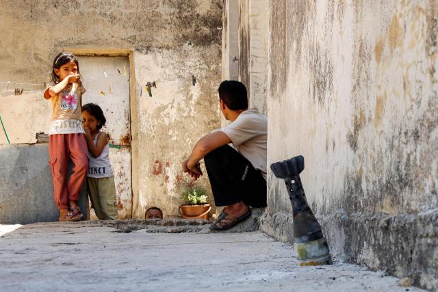 A man speaks with a child while sitting near an unexploded artillery shell that fell during reported overnight Israeli bombardment that hit the village of Abidin in Syria's southwestern Daraa province, close to the Golan Heights, on June 29, 2026. Syria's foreign ministry condemned on June 29 Israeli incursions and shelling in the south of the country, a day after an escalation in the village in Daraa province forced its residents to temporarily flee, according to local officials. (Photo by Sam HARIRI / AFP)