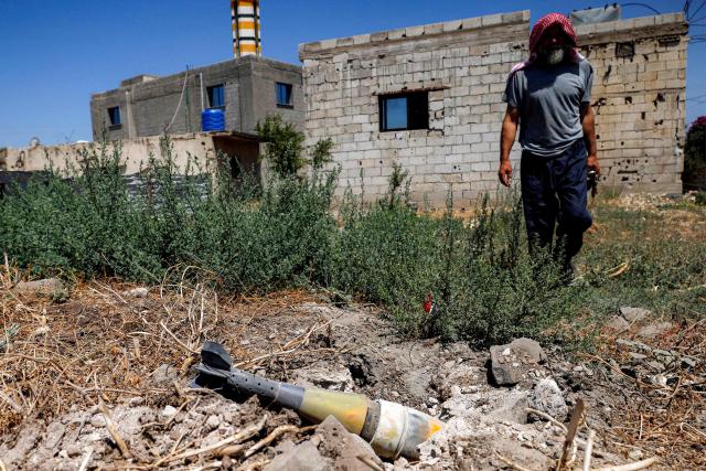 A man stands near an unexploded artillery shell that fell during reported overnight Israeli bombardment that hit the village of Abidin in Syria's southwestern Daraa province, close to the Golan Heights, on June 29, 2026. Syria's foreign ministry condemned on June 29 Israeli incursions and shelling in the south of the country, a day after an escalation in the village in Daraa province forced its residents to temporarily flee, according to local officials. (Photo by Sam HARIRI / AFP)