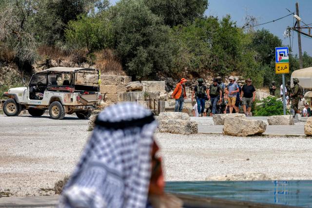 A Palestinian man looks on near Israeli settlers gathering during an official visit by a group of foreign diplomats accredited by the Palestinian Authority at the archaeological site of Sebastia, north of Nablus in the occupied West Bank, on June 29, 2026. (Photo by Jaafar ASHTIYEH / AFP)