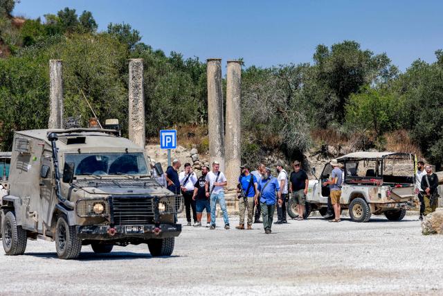 Israeli settlers are pictured near Israeli military vehicles during an official visit by a group of foreign diplomats accredited by the Palestinian Authority at the archaeological site of Sebastia, north of Nablus in the occupied West Bank, on June 29, 2026. (Photo by Jaafar ASHTIYEH / AFP)