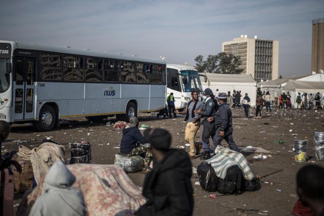 eThekwini Metro Police officers confront an undocumented migrants as others are seen queueing to board busses at the Durban Drive In in Durban, on June 29, 2026 preparing to leave before the camp will shut down and the operation will be transferred to the border with Zimbabwe. South Africans President Cyril Ramaphosa vowed on June 25 to crush any attempts to destabilise the nation during planned anti-immigrant marches next week, amid a wave of xenophobia. Citizen-led groups have set Tuesday 30 as a deadline for undocumented foreigners to leave and called for nationwide marches against illegal immigration, marking a crescendo in months of protests that have at times turned violent. (Photo by MARCO LONGARI / AFP)