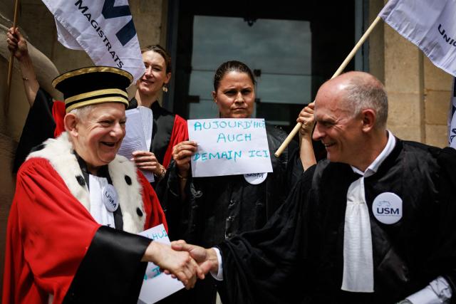 A lawyer (C) holds a placard reading "Today Auch, Tomorrow here" as protesters gather on the steps of the Paris Courthouse while taking part in a "Dead Criminal Justice" day of action called by the council of the Order of the Paris Bar to fight against the "SURE" (Useful, Fast and Effective Sentencing) draft bill, in Paris on June 29, 2026. (Photo by SIMON WOHLFAHRT / AFP)