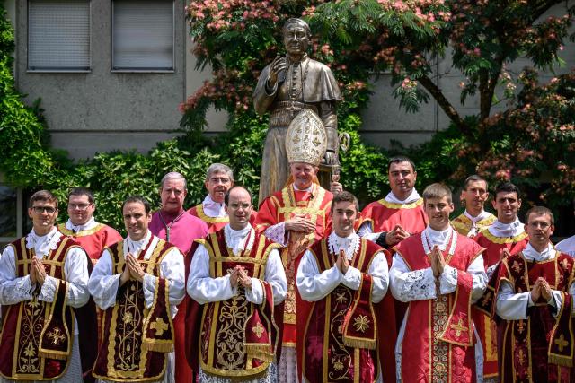 Swiss traditionalist Catholic Bishop and former Superior General of the Society of Saint Pius X (SSPX) Bernard Fellay, priests and deacons pose next to a statue of Saint Pius X after an ordination ceremony of the traditionalist Catholic Society of Saint Pius X (SSPX), in Econe, near Sion, western Switzerland, on June 29, 2026. Defying Vatican, Society of Saint Pius X will ordain its own bishops on July 1, 2026, despite the risk of being considered schismatic. (Photo by Fabrice COFFRINI / AFP)