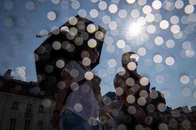 (FILES) People shelter from the sun under umbrellas as they walk on the Royal Castle Square in Warsaw's Old Town as thermometers show record temperatures during a heatwave that has reached Poland on 28 June 2026. At least 130 million people in Europe, mainly located in the central and eastern parts of the continent, are set for temperatures exceeding 35C on June 29, 2026, according to AFP calculations. (Photo by Wojtek RADWANSKI / AFP)