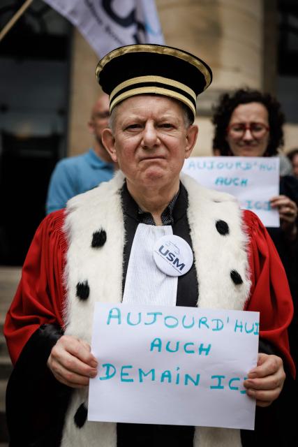 A judge holds a placard reading "Today Auch, Tomorrow here"  as protesters gather on the steps of the Paris Courthouse during the "Dead Criminal Justice" day of action called by the council of the Order of the Paris Bar to fight against the "SURE" (Useful, Fast and Effective Sentencing) draft bill, in Paris on June 29, 2026. (Photo by SIMON WOHLFAHRT / AFP)