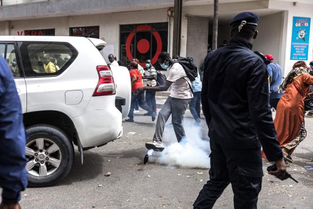 TOPSHOT - A protester kicks a teargas canister thrown by Senegalese police officers during a demonstration against a constitutional reform bill near the National Assembly in Dakar, on June 29, 2026. Senegal’s National Assembly was examining, in a tense atmosphere marked by heated exchanges between lawmakers and clashes between demonstrators and police outside the building, a bill revising the Constitution concerning the powers of the President, Parliament, and the Prime Minister. The initiative, put forward by the parliamentary majority and its leader Ousmane Sonko, comes amid a deep disagreement with the country’s president. (Photo by PATRICK MEINHARDT / AFP)