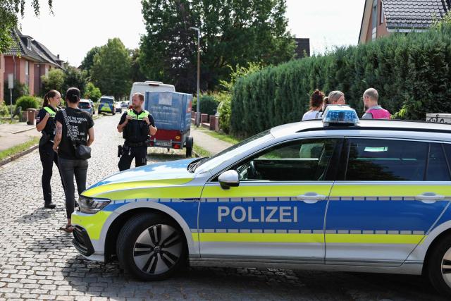 Police speak to people near the scene where five people were killed in a shooting in Stade, northern Germany, a city some 50 kilometres west of Hamburg, on June 29, 2026. German police said five people were killed and others injured on June 29, 2026 in a shooting in a youth welfare facility in the northern city of Stade. Two people were arrested, including the suspected shooter, and there was now "no danger to the public", local police said in an update around 1215 GMT. (Photo by Ibrahim OT / AFP)