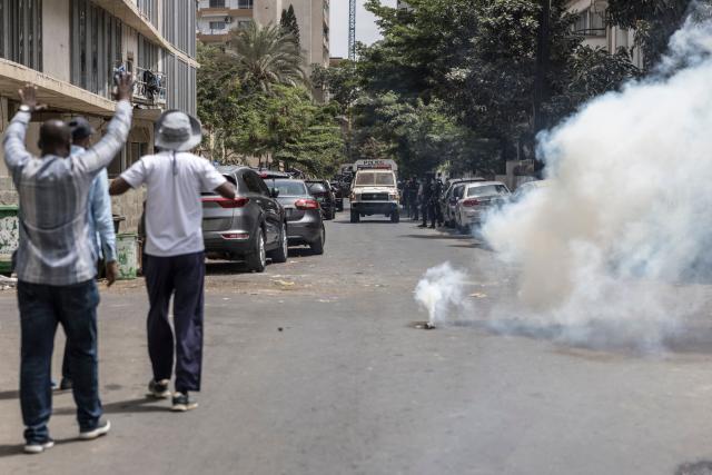Protesters gesture at Senegalese police officers after they fired a teargas canister during a demonstration against a constitutional reform bill near the National Assembly in Dakar, on June 29, 2026. Senegal’s National Assembly was examining, in a tense atmosphere marked by heated exchanges between lawmakers and clashes between demonstrators and police outside the building, a bill revising the Constitution concerning the powers of the President, Parliament, and the Prime Minister. The initiative, put forward by the parliamentary majority and its leader Ousmane Sonko, comes amid a deep disagreement with the country’s president. (Photo by PATRICK MEINHARDT / AFP)