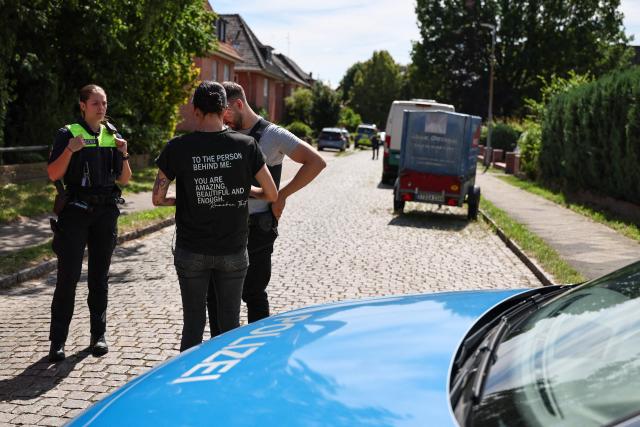 Police speak to a woman near the scene where five people were killed in a shooting in Stade, northern Germany, a city some 50 kilometres west of Hamburg, on June 29, 2026. German police said five people were killed and others injured on June 29, 2026 in a shooting in a youth welfare facility in the northern city of Stade. Two people were arrested, including the suspected shooter, and there was now "no danger to the public", local police said in an update around 1215 GMT. (Photo by Ibrahim OT / AFP)