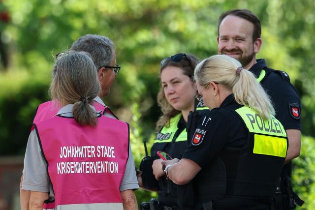 Police officers speak with members of a crisis intervention team near the scene where five people were killed in a shooting in Stade, northern Germany, a city some 50 kilometres west of Hamburg, on June 29, 2026. German police said five people were killed and others injured on June 29, 2026 in a shooting in a youth welfare facility in the northern city of Stade. Two people were arrested, including the suspected shooter, and there was now "no danger to the public", local police said in an update around 1215 GMT. (Photo by Ibrahim OT / AFP)