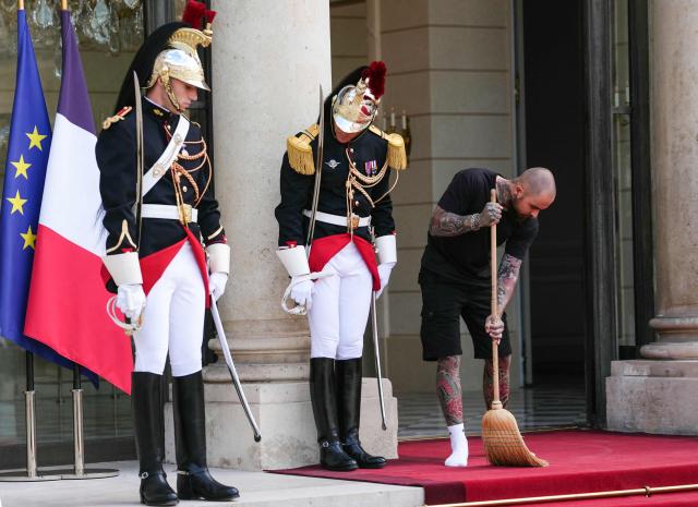 Elysee Presidential Palace's worker sweeps next to members of the Republican Guard (Guarde Republicaine) ahead of a meeting between France's President and Thailand's King at The Elysee Presidential Palace in Paris on June 29, 2026. (Photo by Dimitar DILKOFF / AFP)