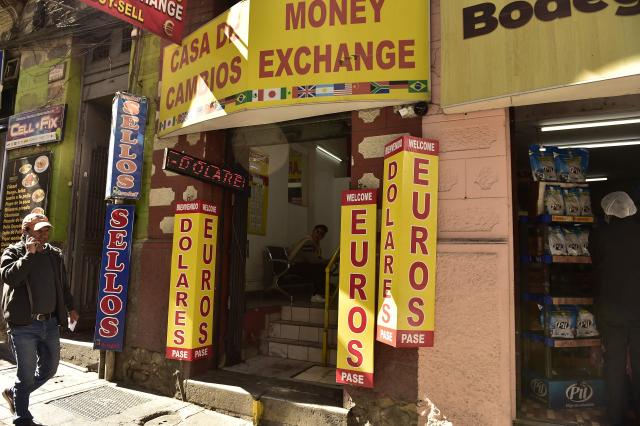 A man walks outside a currency exchange bureau in downtown La Paz on June 29, 2026. Bolivia lifted a 15-year peg on its dollar exchange rate in a bid to attract more greenbacks, a move aimed at ending a severe economic crisis that has sparked unrest. (Photo by Jorge BERNAL / AFP)