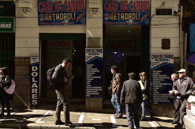 People are seen outside a currency exchange bureau in downtown La Paz on June 29, 2026. Bolivia lifted a 15-year peg on its dollar exchange rate in a bid to attract more greenbacks, a move aimed at ending a severe economic crisis that has sparked unrest. (Photo by Jorge BERNAL / AFP)