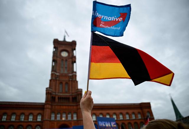 A supporter of the far-right Alternative for Germany (AfD) party waves their party's flag and a German flag at a campaign rally in front ot the Berlin City Hall on June 29, 2026. (Photo by Tobias SCHWARZ / AFP)