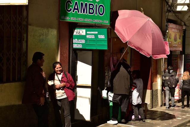 People are seen outside a currency exchange bureau in downtown La Paz on June 29, 2026. Bolivia lifted a 15-year peg on its dollar exchange rate in a bid to attract more greenbacks, a move aimed at ending a severe economic crisis that has sparked unrest. (Photo by Jorge BERNAL / AFP)