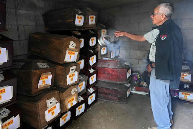 A man burns incense next to funeral urns during the burial of people relative killed during the internal armed conflict (1960-1996), at a cemetery in Pacoj village, San Martin Jilotepeque, Guatemala on June 29, 2026. The remains of 68 people -- victims of the 36-year internal armed conflict -- were buried on June 29, 2026. According to the Commission for Historical Clarification, more than 200,000 people were killed or disappeared in the civil war. (Photo by JOHAN ORDONEZ / AFP)