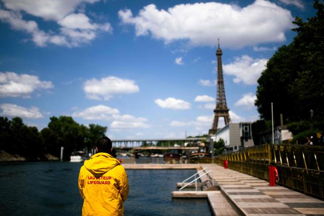 A lifeguard looks at the Seine river at the Baignade de Grenelle Baignade safe swimming site with the Eiffel Tower in the background, in Paris on June 29, 2026. The Baignade de Grenelle Baignade safe swimming will open on July 4, 2026. (Photo by Julie SEBADELHA / AFP)