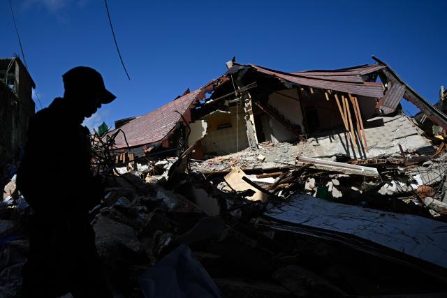 A Venezuelan national police officer of the Criminal Gang Unit stands guard next to rubble in El Junquito, Venezuela on June 29, 2026, after twin earthquakes. Hopes were fading on June 29, 2026 of finding survivors more than four days after powerful twin earthquakes struck Venezuela, as residents grow increasingly frustrated with the government's response to the disaster that has killed at least 1,450 people and left tens of thousands unaccounted for. (Photo by Federico PARRA / AFP)