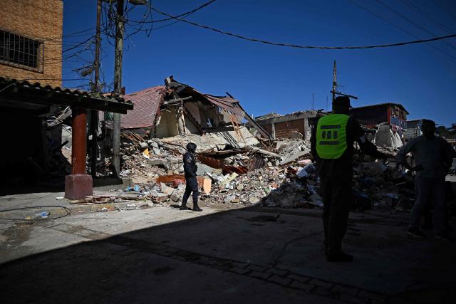 Police officers stand guard near rubble in El Junquito, Venezuela on June 29, 2026, after twin earthquakes. Hopes were fading on June 29, 2026 of finding survivors more than four days after powerful twin earthquakes struck Venezuela, as residents grow increasingly frustrated with the government's response to the disaster that has killed at least 1,450 people and left tens of thousands unaccounted for. (Photo by Federico PARRA / AFP)