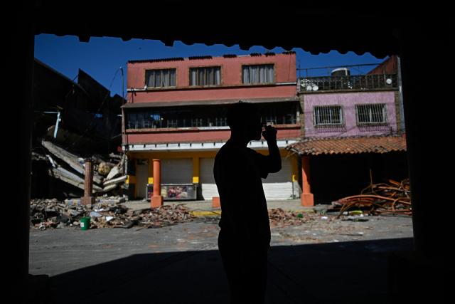 A man is seen near damaged buildings in El Junquito, Venezuela on June 29, 2026, after twin earthquakes. Hopes were fading on June 29, 2026 of finding survivors more than four days after powerful twin earthquakes struck Venezuela, as residents grow increasingly frustrated with the government's response to the disaster that has killed at least 1,450 people and left tens of thousands unaccounted for. (Photo by Federico PARRA / AFP)