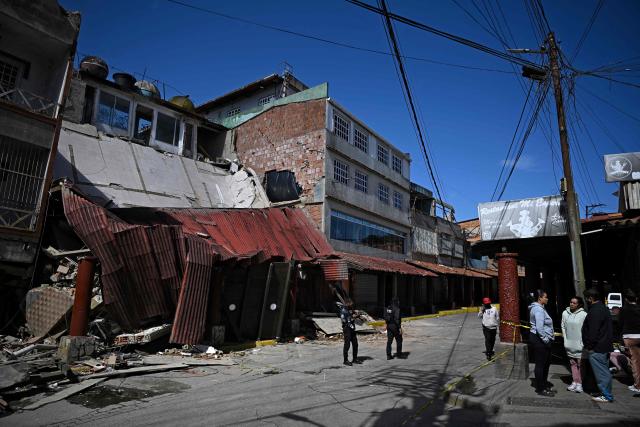 Venezuelan national police officers of the Criminal Gang Unit stand guard outside food stores affected by the quakes in El Junquito, Venezuela on June 29, 2026. Hopes were fading on June 29, 2026 of finding survivors more than four days after powerful twin earthquakes struck Venezuela, as residents grow increasingly frustrated with the government's response to the disaster that has killed at least 1,450 people and left tens of thousands unaccounted for. (Photo by Federico PARRA / AFP)