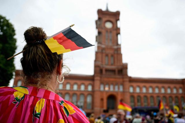 A supporter of the far-right Alternative for Germany (AfD) party wears a German flag in her hair as she attends a campaign rally in front of the Berlin City Hall on June 29, 2026. (Photo by Tobias SCHWARZ / AFP)