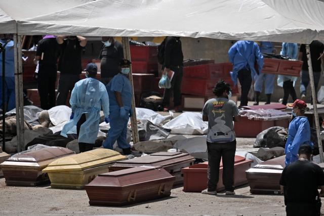 Forensic experts stand amid victims and coffins in La Guaira, La Guaira State, Venezuela on June 29, 2026, following the June 24 twin earthquakes. Hopes were fading on June 29, 2026 of finding survivors more than four days after powerful twin earthquakes struck Venezuela, as residents grow increasingly frustrated with the government's response to the disaster that has killed at least 1,450 people and left tens of thousands unaccounted for. (Photo by Juan BARRETO / AFP)