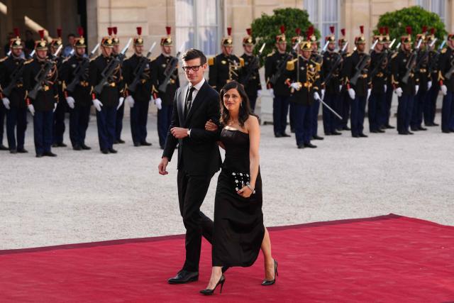 France’s junior Minister in charge of global Francophones and expatriates Eleonore Caroit (R) and her partner Roman Pinosch (L) arrive at The Elysee Presidential Palace for a working dinner with France's President and Thailand's King Maha Vajiralongkorn as part of the Thai King's State visit to France, in Paris on June 29, 2026.  (Photo by Dimitar DILKOFF / AFP)