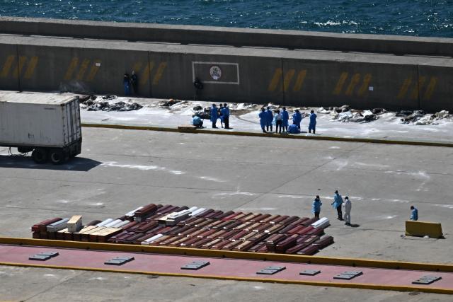 Forensic experts stand next to victims and coffins in the port of La Guaira, La Guaira State, Venezuela on June 29, 2026, following the June 24 twin earthquakes. Hopes were fading on June 29, 2026 of finding survivors more than four days after powerful twin earthquakes struck Venezuela, as residents grow increasingly frustrated with the government's response to the disaster that has killed at least 1,450 people and left tens of thousands unaccounted for. (Photo by Juan BARRETO / AFP)