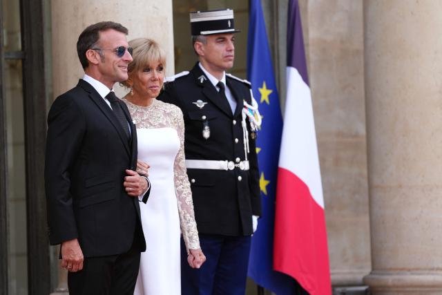 France's President Emmanuel Macron (L) and his wife Brigitte Macron (C) wait to greet Thailand's King Maha Vajiralongkorn on the steps of The Elysee Presidential Palace ahead of a working dinner as part of the Thai King's State visit to France, in Paris on June 29, 2026. (Photo by Dimitar DILKOFF / AFP)