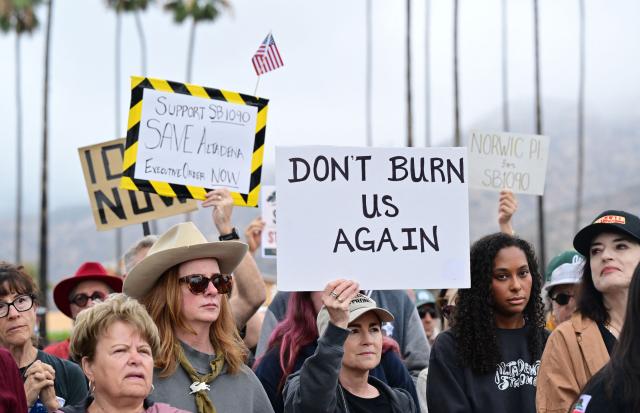 Survivors of the 2025 Eaton Fire hold signs during a demonstration in Altadena, California, on June 29, 2026. Altadena residents are expressing support of California Senate Bill SB 1090, which addresses disaster recovery, restricting rapid large-scale investor purchases and exemptions in fire-damaged areas from dense housing laws, allowing for local residents to rebuild without having coprporate buyers displace them. (Photo by Frederic J. BROWN / AFP)