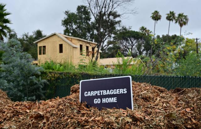 A sign is posted in front of a new home under construction as survivors of the 2025 Eaton Fire hold a demonstration in Altadena, California, on June 29, 2026. Altadena residents are expressing support of California Senate Bill SB 1090, which addresses disaster recovery, restricting rapid large-scale investor purchases and exemptions in fire-damaged areas from dense housing laws, allowing for local residents to rebuild without having coprporate buyers displace them. (Photo by Frederic J. BROWN / AFP)