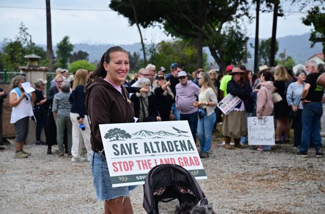 A survivor of the 2025 Eaton Fire holds a sign during a demonstration in Altadena, California, on June 29, 2026. Altadena residents are expressing support of California Senate Bill SB 1090, which addresses disaster recovery, restricting rapid large-scale investor purchases and exemptions in fire-damaged areas from dense housing laws, allowing for local residents to rebuild without having coprporate buyers displace them. (Photo by Frederic J. BROWN / AFP)
