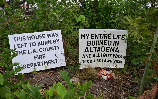 Signs are posted at a fire-damaged property as survivors of the 2025 Eaton Fire hold a demonstration in Altadena, California, on June 29, 2026. Altadena residents are expressing support of California Senate Bill SB 1090, which addresses disaster recovery, restricting rapid large-scale investor purchases and exemptions in fire-damaged areas from dense housing laws, allowing for local residents to rebuild without having coprporate buyers displace them. (Photo by Frederic J. BROWN / AFP)
