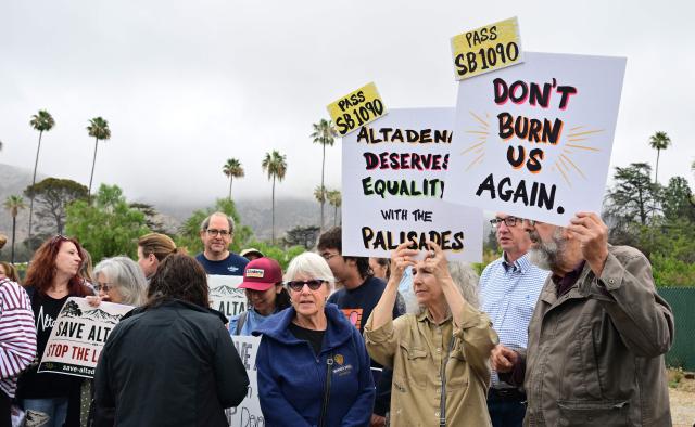 Survivors of the 2025 Eaton Fire hold signs during a demonstration in Altadena, California, on June 29, 2026. Altadena residents are expressing support of California Senate Bill SB 1090, which addresses disaster recovery, restricting rapid large-scale investor purchases and exemptions in fire-damaged areas from dense housing laws, allowing for local residents to rebuild without having coprporate buyers displace them. (Photo by Frederic J. BROWN / AFP)