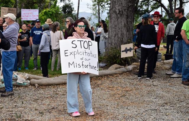 Survivors of the 2025 Eaton Fire hold signs during a demonstration in Altadena, California, on June 29, 2026. Altadena residents are expressing support of California Senate Bill SB 1090, which addresses disaster recovery, restricting rapid large-scale investor purchases and exemptions in fire-damaged areas from dense housing laws, allowing for local residents to rebuild without having coprporate buyers displace them. (Photo by Frederic J. BROWN / AFP)