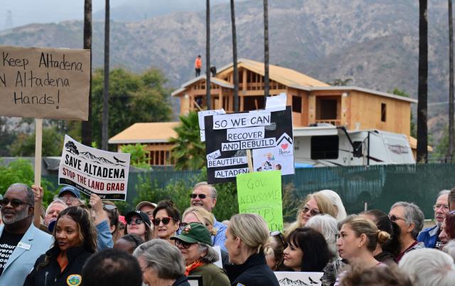 As a new house is under construction, survivors of the 2025 Eaton Fire hold signs during a demonstration in Altadena, California, on June 29, 2026. Altadena residents are expressing support of California Senate Bill SB 1090, which addresses disaster recovery, restricting rapid large-scale investor purchases and exemptions in fire-damaged areas from dense housing laws, allowing for local residents to rebuild without having coprporate buyers displace them. (Photo by Frederic J. BROWN / AFP)