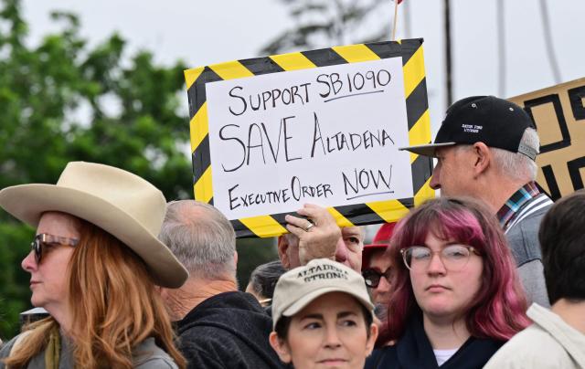 Survivors of the 2025 Eaton Fire hold signs during a demonstration in Altadena, California, on June 29, 2026. Altadena residents are expressing support of California Senate Bill SB 1090, which addresses disaster recovery, restricting rapid large-scale investor purchases and exemptions in fire-damaged areas from dense housing laws, allowing for local residents to rebuild without having coprporate buyers displace them. (Photo by Frederic J. BROWN / AFP)