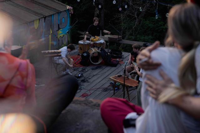 Visitors listen to a concert at the Gak garage art cooperative on a hot evening in Kyiv on June 28, 2026, amid the Russian invasion of Ukraine. Volunteers from 'Repair Together' transformed a site within a garage co-operative into GAK, a cultural space hosting concerts, exhibitions, lectures and community events. 'Repair Together' has been rebuilding villages in Ukraine's Chernihiv region since the area was liberated from Russian forces. (Photo by Tetiana DZHAFAROVA / AFP)