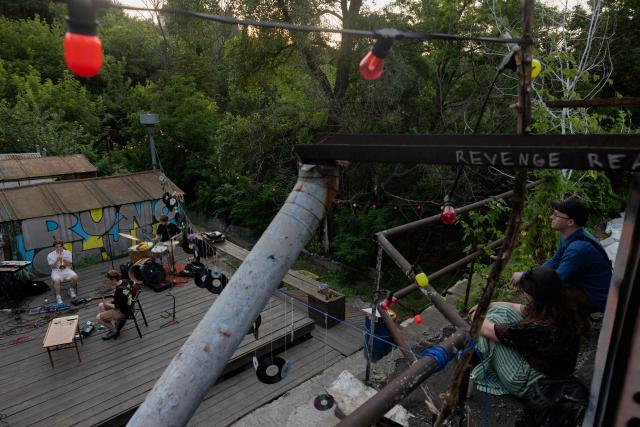 Visitors listen to a concert at the Gak garage art cooperative on a hot evening in Kyiv on June 28, 2026, amid the Russian invasion of Ukraine. Volunteers from 'Repair Together' transformed a site within a garage co-operative into GAK, a cultural space hosting concerts, exhibitions, lectures and community events. 'Repair Together' has been rebuilding villages in Ukraine's Chernihiv region since the area was liberated from Russian forces. (Photo by Tetiana DZHAFAROVA / AFP)