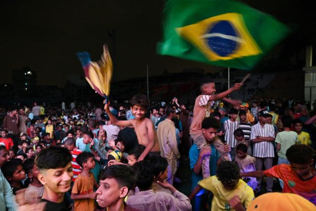 Children celebrate Brazil's victory by waving a Brazilian flag after watching a live broadcast of the 2026 World Cup round of 32 football match between Brazil and Japan, at a fanzone in Karachi on June 29, 2026. (Photo by Asif HASSAN / AFP)