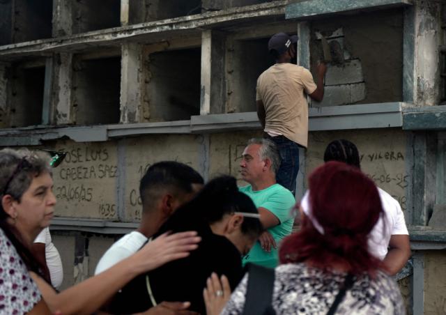A cemetery worker seals a niche of a victim of the June 24 twin earthquakes, as relatives wait to pay last respects during the burial at the Cementerio General del Sur (Southern General Cemetery) in Caracas on June 29, 2026. Hopes were fading on June 29, 2026 of finding survivors more than four days after powerful twin earthquakes struck Venezuela, as residents grow increasingly frustrated with the government's response to the disaster that has killed -up to now- more than 1,700 people and left tens of thousands unaccounted for. (Photo by Rosali Hernandez / AFP)