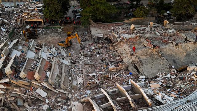 This aerial picture shows a backhoe loader working at the site of buildings destroyed during the June 24 twin earthquakes, in Caraballeda, La Guaira State, Venezuela, on June 29, 2026. Volunteers and emergency brigades with rescue dogs continue lifting mountains of rubble in search of survivors of the twin earthquake that struck Venezuela four days ago, which completely brought down nearly 200 buildings and left more than 1,700 dead and tens of thousands missing. (Photo by Miguel MEDINA / POOL / AFP)