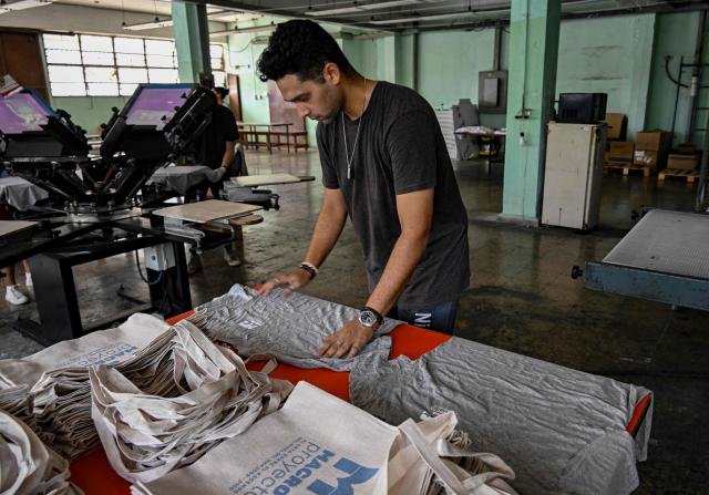 A man works at the private screen-printing business La Cabra Studio in Havana on June 22, 2026. Food, transport and even fuel imports: the private sector, once marginal, is now establishing itself in a Cuba in crisis and is set to grow further following the recent liberalisation measures approved by the government. (Photo by YAMIL LAGE / AFP)