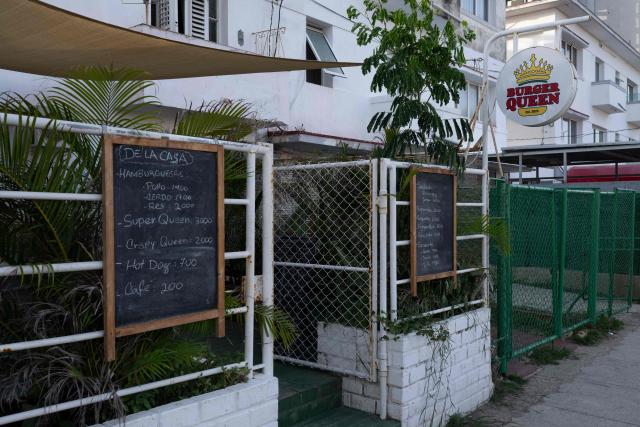 A board listing products and prices is displayed outside the private business Burger Queen in Havana on June 23, 2026. Food, transport and even fuel imports: the private sector, once marginal, is now establishing itself in a Cuba in crisis and is set to grow further following the recent liberalisation measures approved by the government. (Photo by PABLO  PORCIUNCULA / AFP)