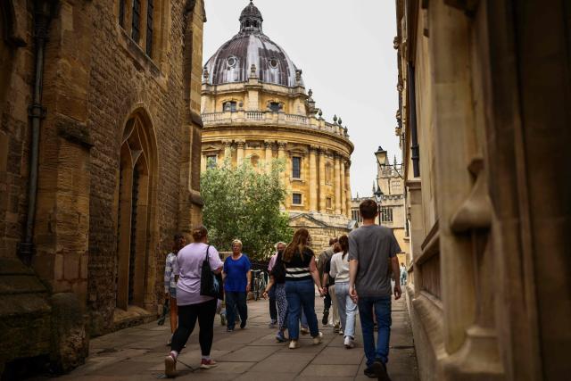 This photo taken on June 17, 2026 shows people walking past the Radcliffe Camera building at Oxford University in Oxford, central England. With its grand atrium, 500-seat acoustics-led concert hall and other state-of-the-art spaces, Oxford's Schwarzman Centre is the newest example of an elite UK university showcasing a billionaire's endowment. (Photo by HENRY NICHOLLS / AFP) / TO GO WITH Britain-education-universities-philanthrophy,FOCUS by Joe JACKSON